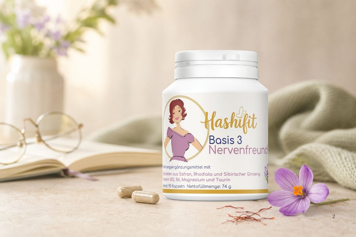 Hashifit Basis 3 Nervenfreund auf einem Tisch neben Buch, Lesebrille und Safranblüte. Vor der Dose liegen zwei Kapseln.
