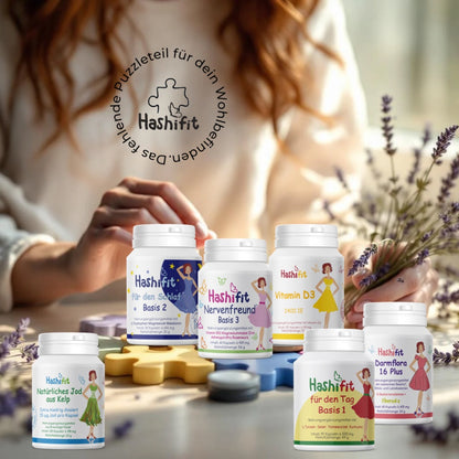 Hashifit Unterstützungspaket mit Basis 1, Basis 2, Basis 3, Vitamin D3, Jod aus Kelp und Darmflora 16 Plus auf weißen Podesten vor zartlila Hintergrund